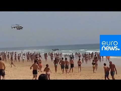 شاهد زورقٌ للمهاجرين المغاربة يرسو على شاطئ إسباني وسط آلاف السياح