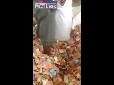 رجل يقف وسط غرفة ممتلئة بالنقود الورقية